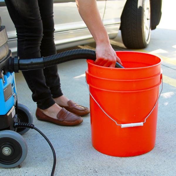 Mytee 8070 Lite Heated Detailing Extractor, filling the solution tank from a bucket beside a vehicle